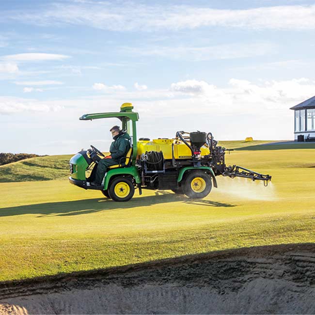 Vejos prižiūrėtojas dirba vejos plote su John Deere purkštuvu