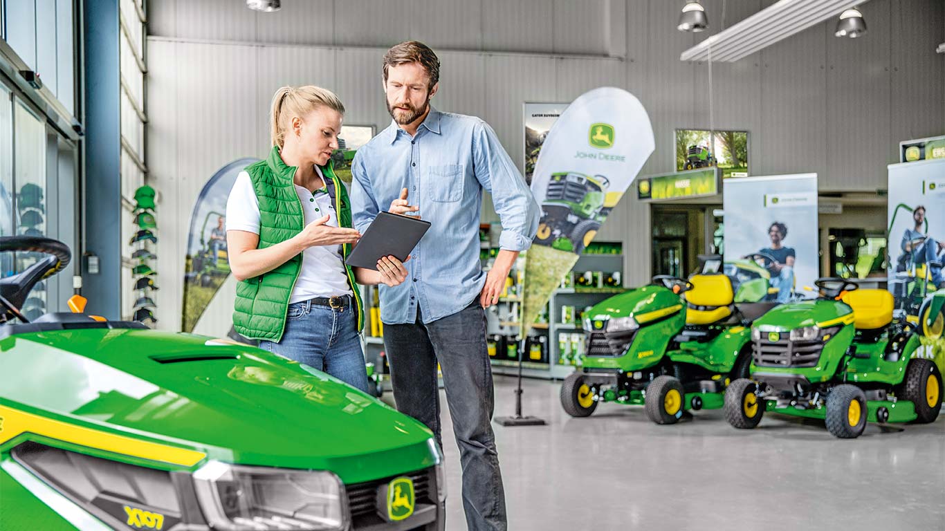 John Deere įgaliotas atstovas konsultuoja klientą, kuris nori įsigyti John Deere vejapjovę.