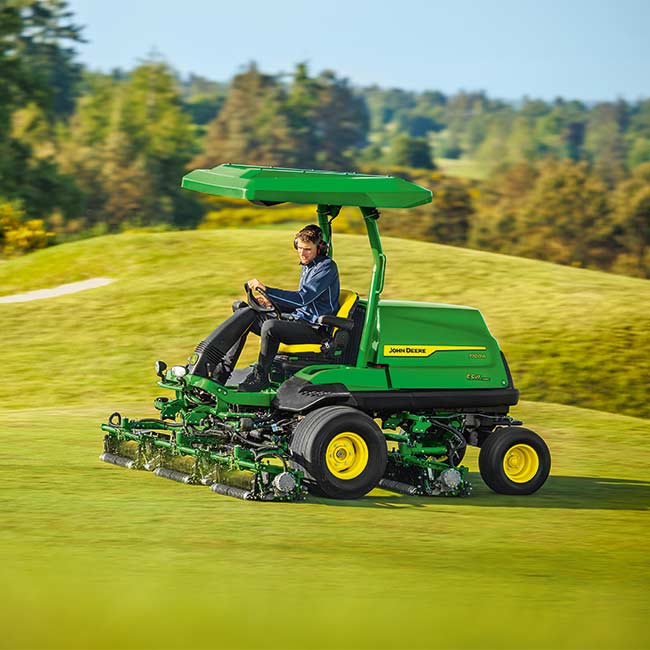 Vejos prižiūrėtojas dirba vejos plote su John Deere golfo laukų vejapjove