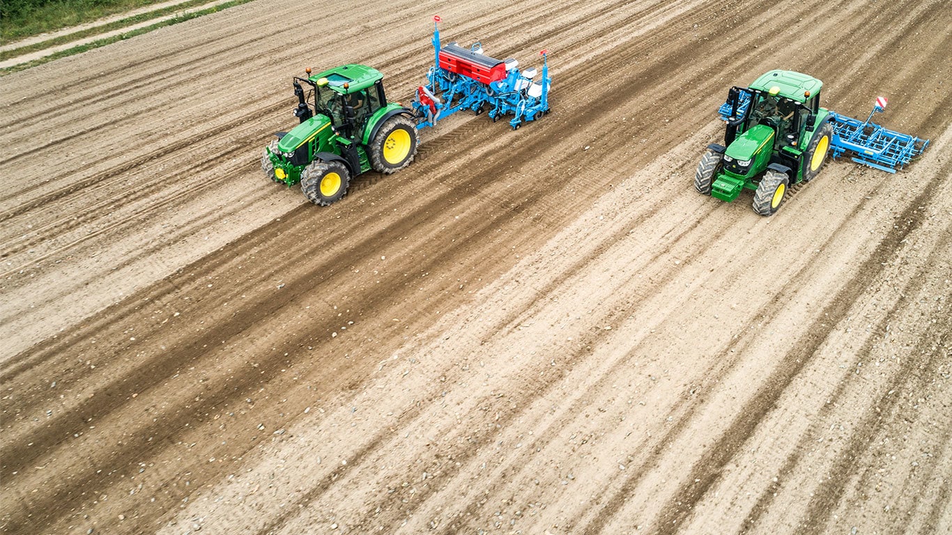 Du &bdquo;John Deere&ldquo; 6M traktoriai ant plikos žemės. Vienas traukia &bdquo;Monsomen&ldquo; sodinamąją. Kitas &ndash; &bdquo;Lemken&ldquo; sėjamosios junginį