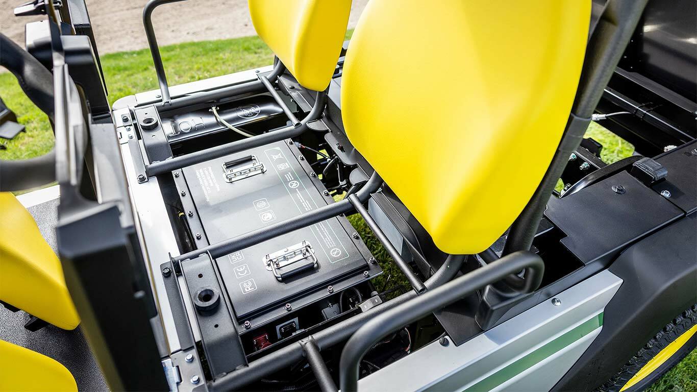 Dviejų ličio akumuliatorių rinkinių, sumontuotų po ryškiai geltonomis sėdynėmis "John Deere Gator GS" elektriniame universaliajame visureigyje, vaizdas iš arti.