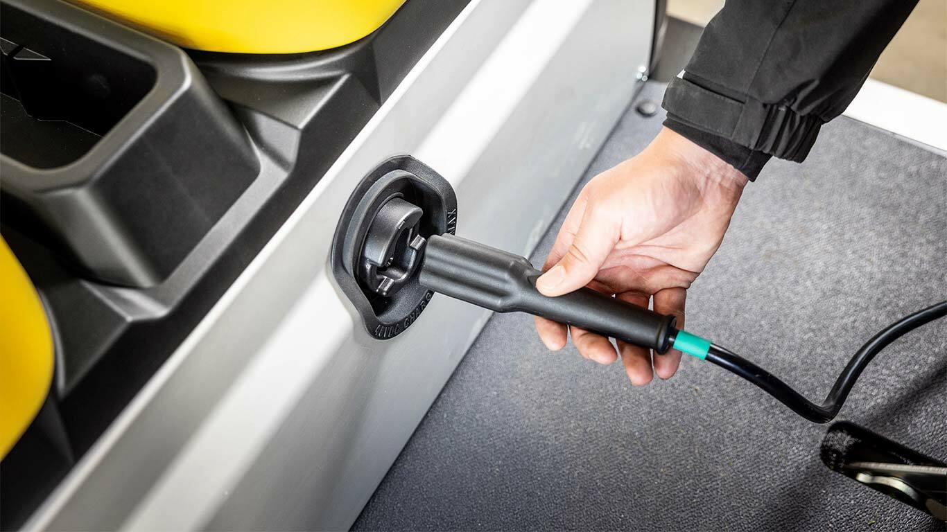 Įkrovimo kabelio prijungimas ranka prie "John Deere Gator GS" elektrinio universaliojo visureigio šoninio prievado.