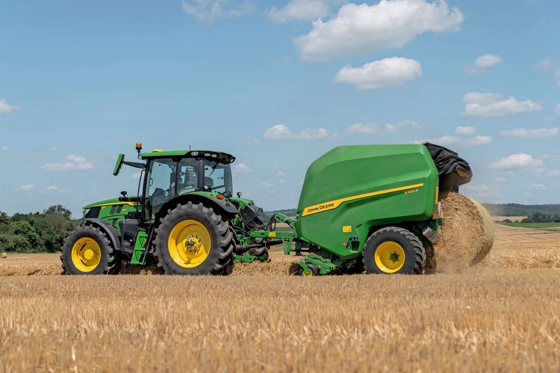 John Deere 6R 150 velkamas "John Deere" V452R šiaudų lauke, išmetantis ryšulį
