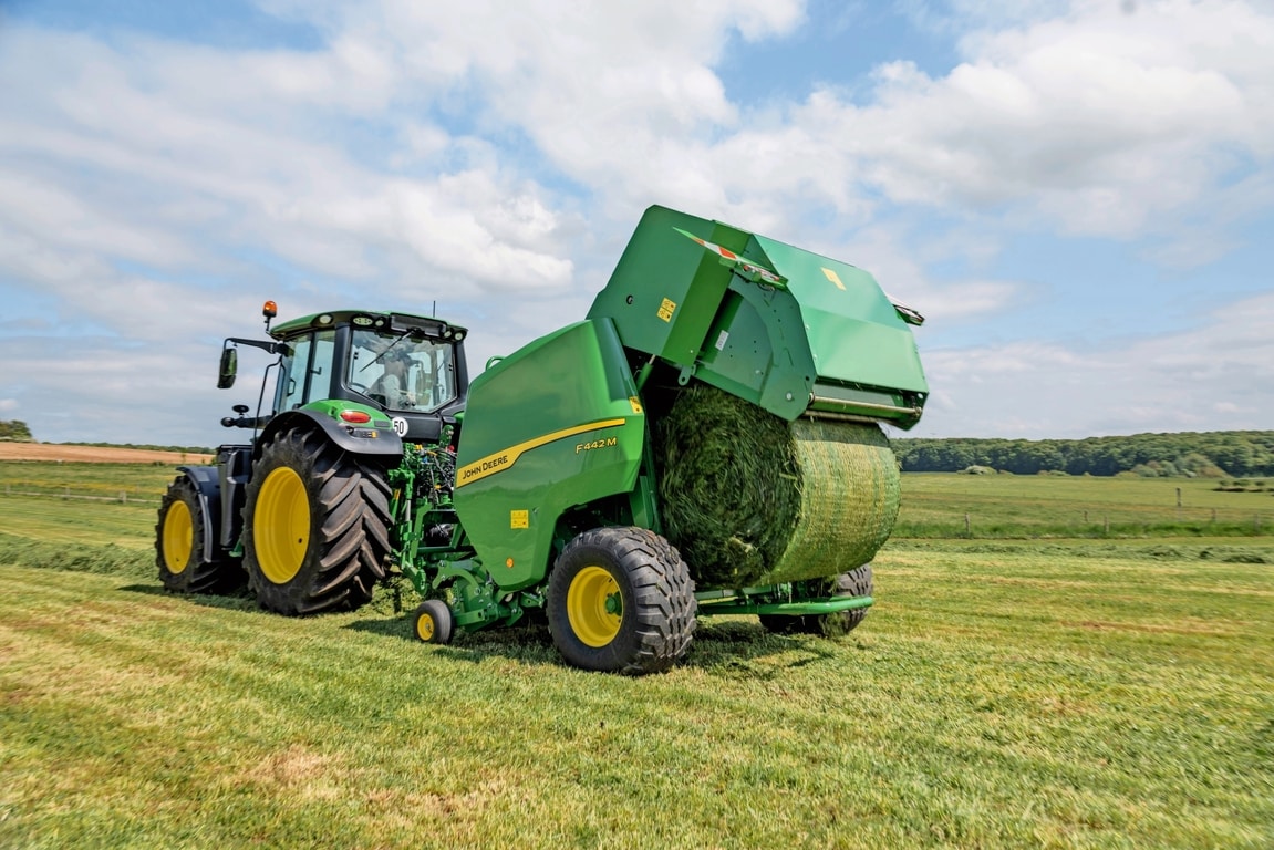 John Deere 6M traktoriaus velkamas F442M ryšulių presas, išmetantis žolės ryšulį