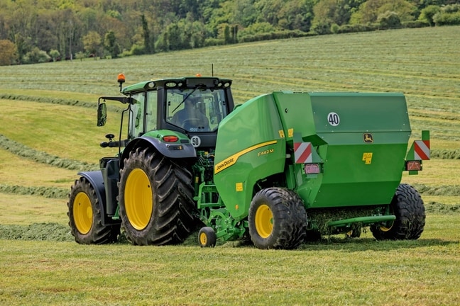 John Deere 6M traktoriaus velkamas "John Deere" F442M ryšulių presas kalvotoje pievoje