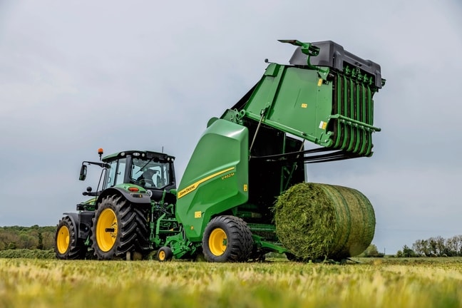 John Deere 6M traktoriaus velkamas V462M ryšulių presas, išmetantis žolės ryšulį
